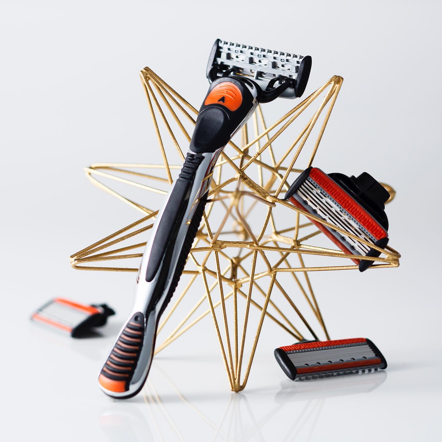 Orange and black GALLEIDO men's shaving razor arranged on a wicker star with replaceable blades